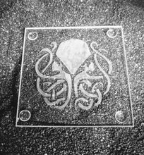 Load image into Gallery viewer, A clear glass coaster etched with a celtic knotwork design of Cthulhu. 
