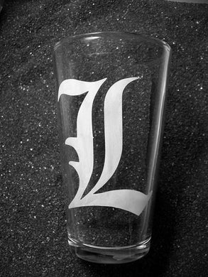 A pint glass etched with a Large capital L in Old English font. 