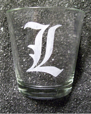 A shot glass etched with a capital L in Old English Font. 