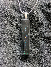 Load image into Gallery viewer, A long skinny rectangle pendant made of glass. The design is black glass with small clusters of glitter sprinkled throughout.