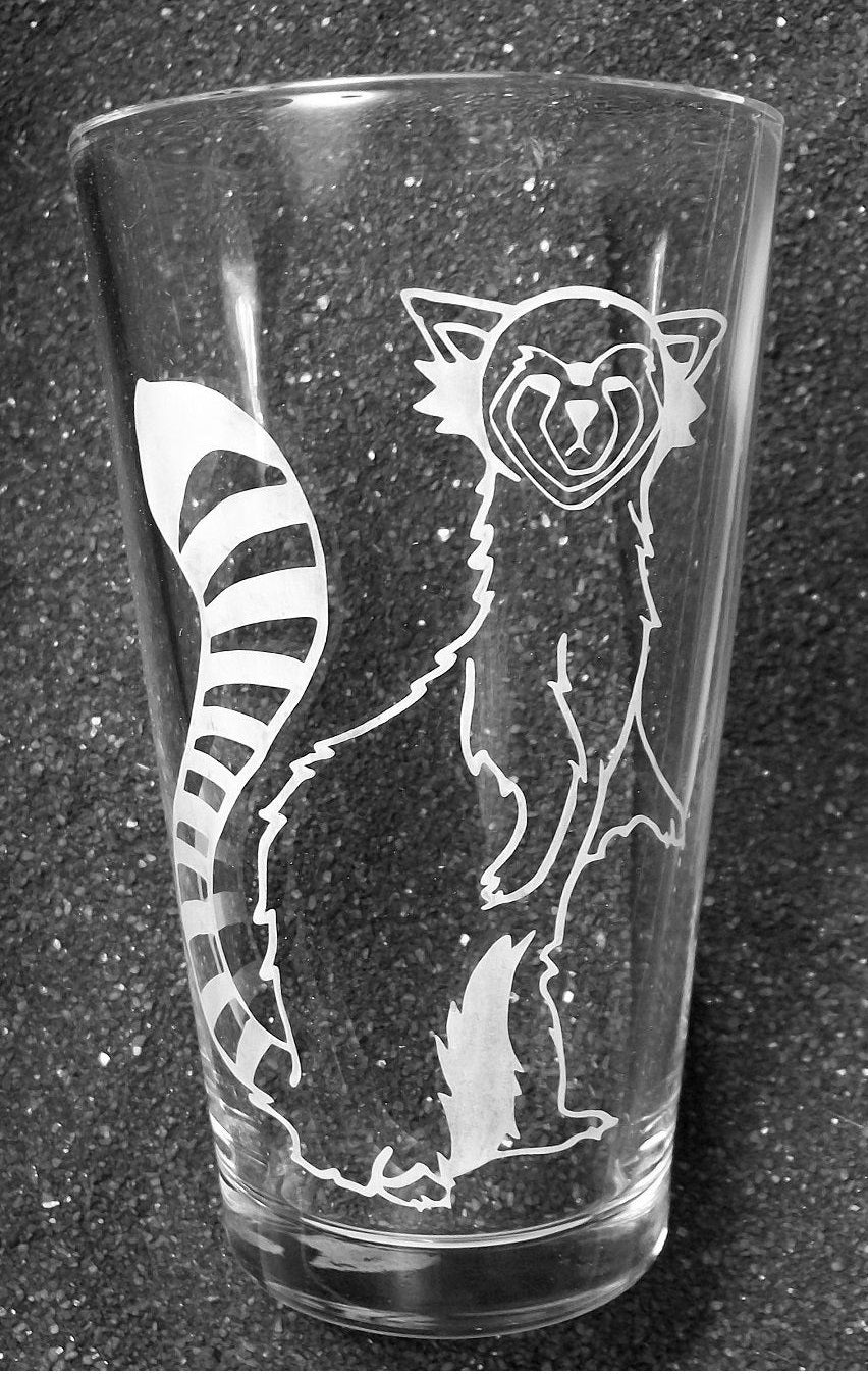 A pint glass etched with Pabu, a fire ferret from Avatar Legend of Korra. He is standing on his hind legs and turning his torso as if looking at the viewer. 