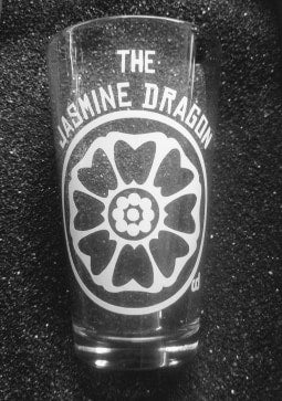 A pint glass with a white lotus design in a circle. Above the circle are the words 