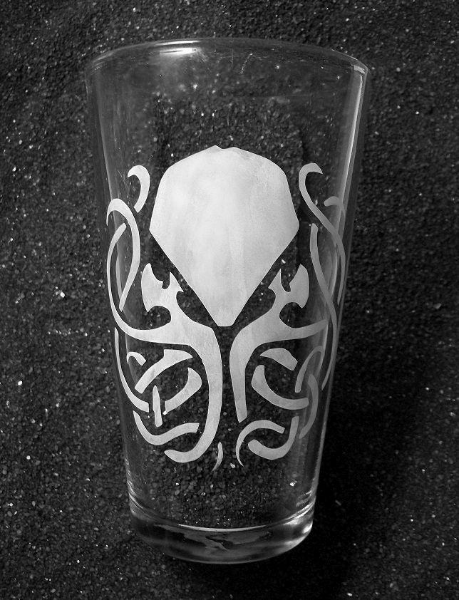 A pint glass featuring an etched design of Cthulhu. His tentacles are twisted into a celtic knot formation. 