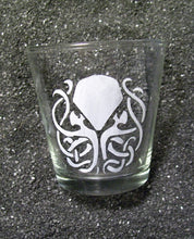 Load image into Gallery viewer, A shot glass featuring an etched design of Cthulhu. His tentacles are twisted into a celtic knot formation. 
