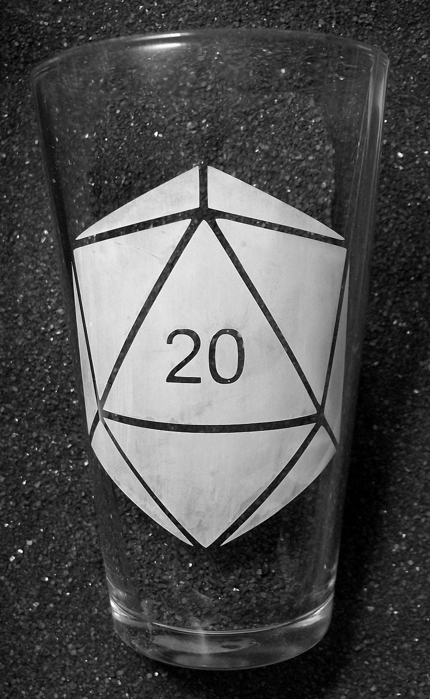 A pint glass with a D20 dice desing. The 20 face is numbered but the other faces are blank. 