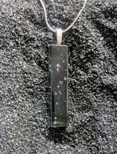 Load image into Gallery viewer, A long skinny rectangle pendant made of glass. The design is black glass with small clusters of glitter sprinkled throughout. 
