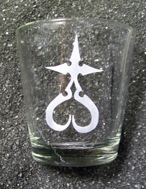 An extra large shot glass etched with a Nobody symbol- a cross, where the bottom 