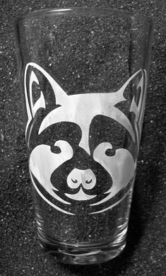 A pint glass etched with a raccoon face looking directly at the viewer. Some customers tell me it looks like a badger to them. 
