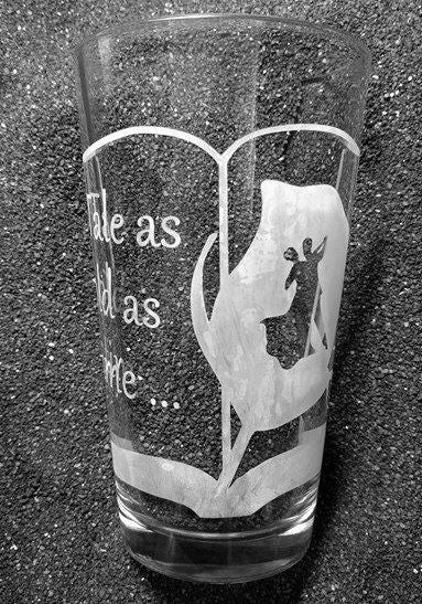 A pint glass etched with an open book frame. The left page reads 