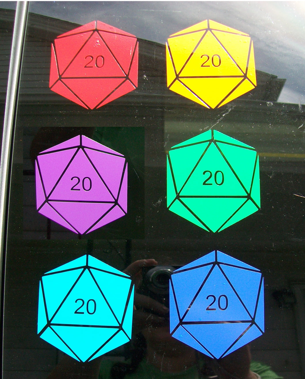 Six different colors of D20 decals on a car window. Each shape has the 20 face numbered but the other faces are blank. 